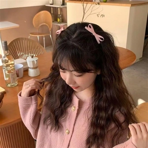 Close-up of pink ribbon bow hair clips worn on both sides of a model's hair