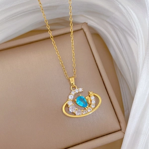 Detailed close-up of a moon and star pendant with a blue teardrop stone on a gold chain