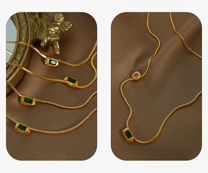 Macro shot of 18K gold plated snake chain necklaces with emerald and ruby zircon pendants