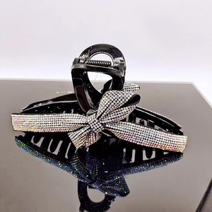 Detailed view of luxury black shark hair clip with sparkling rhinestones and a bow design