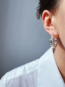 Close-up of silver circular hoop earrings with white pearls on a female model