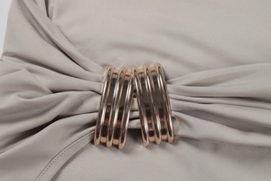 Macro detail of rose gold metal buckle and pleated fabric on bodycon knit dress