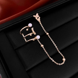 Detailed view of a gold butterfly ear cuff earring with pearls and chains on black leather