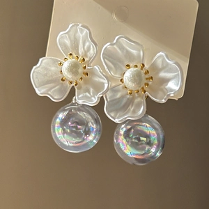 Detailed macro view of white frosted floral earrings with iridescent glass ball drops