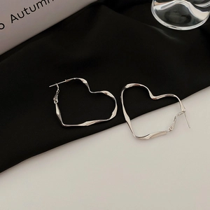 Macro view of silver heart-shaped metal hoop earrings with a smooth polished finish