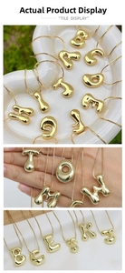 Macro detail of puffy 3D gold bubble letter pendant on a high-polished stainless steel chain