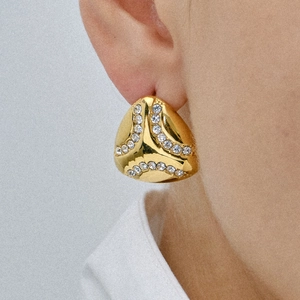 Golden triangular earrings with sparkling rhinestones worn by a model in a retro style