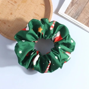 Detail of green Christmas plush hair scrunchie with festive patterns on white background