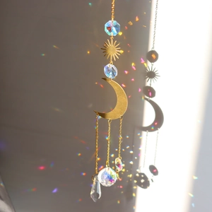 Detail of gold moon sun crystal suncatcher showing rainbow light reflections on the wall