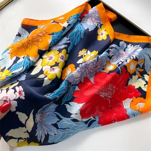 Detailed macro shot of a vibrant floral striped silk scarf with orange borders