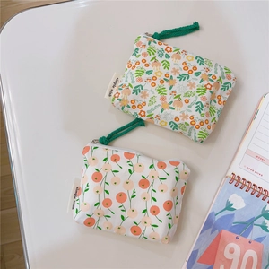 Detail of floral and fruit print canvas coin purses with woven zipper pulls and side labels