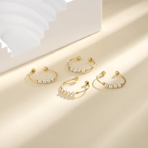 Detail of four golden open rings featuring elegant shell pearls on minimalist bands