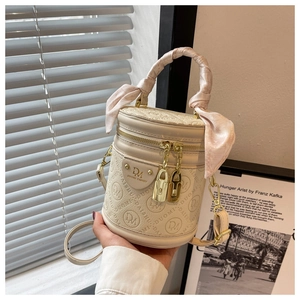 Detail of beige cylinder bucket bag with embossed logo pattern and silk scarf handle wrap