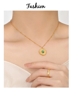 Detailed close-up of fashion gold chain with sunburst green stone pendant and textured ring