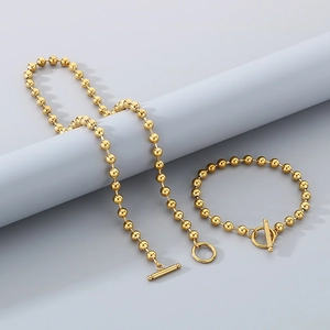 Golden bead necklace and bracelet set with OT toggle clasp on a grey display pedestal