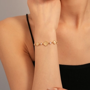 Détail d'un bracelet doré ajustable avec pierres œil de chat et zircons sur le poignet