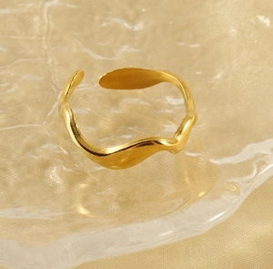 Détail d'une bague ajustable ondulée plaquée or 18K sur un fond en soie élégante