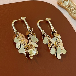 Macro shot of tiered gold teardrop metal sequins on elegant tassel drop earrings