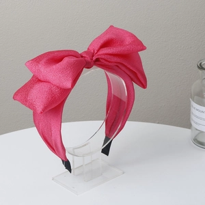 Detail of rose red bow headband with textured fabric on a clear acrylic display stand