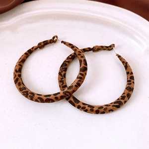 Macro shot of large leopard print earrings with flocked texture on white ceramic tray