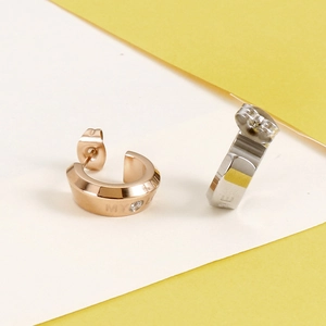 Detailed view of rose gold and silver C-shaped earrings with My Love engraving and zircon