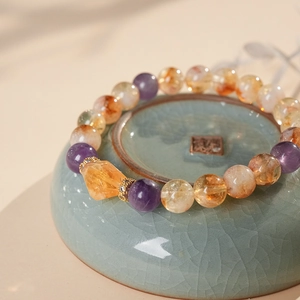 Detailed close-up of amethyst and citrine beaded bracelet inside a ceramic bowl