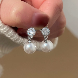 Close-up of elegant silver earrings with round zircon studs and hanging white pearls