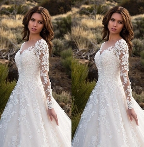 Detail of elegant V-neck wedding dress featuring delicate floral lace and sheer long sleeves