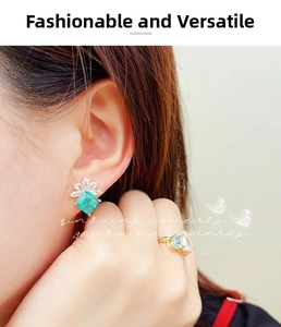Close-up of emerald-cut green earrings and gold ring with pear-shaped stones