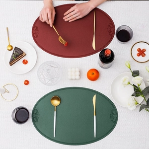 Vintage oval leather placemats in burgundy and dark green with textured borders