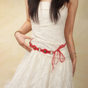 Detail of red leather belt with turquoise inlay worn on a white hollow-out dress