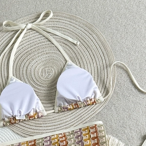 Détail de bikini bohème avec bords crochetés colorés et franges blanches sur le maillot
