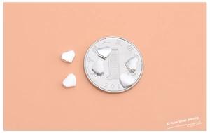 Macro shot of S925 sterling silver heart beads showing size comparison with a coin