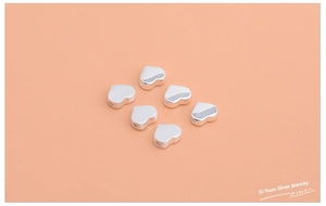 Close-up of six polished S925 sterling silver heart-shaped beads for DIY jewelry making