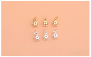 Detailed view of 925 sterling silver star charms with cubic zirconia on pink background