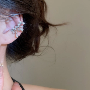 Close-up of silver bow ear cuff with zircon and pearls on model for elegant look