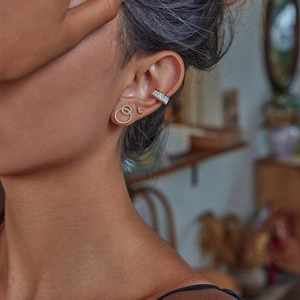 Detail shot of gold ear cuff and interlocking stud earrings set with sparkling crystals