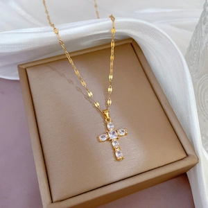 Elegant gold titanium steel cross necklace with pavé zircon stones on jewelry box