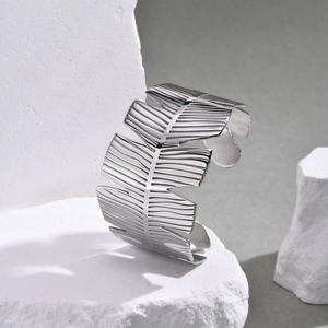 Macro shot of silver feather texture on wide open cuff bracelet made of stainless steel