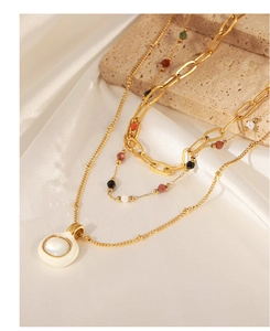 Close-up of layered gold necklaces with white natural stone pendant on silk