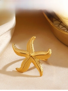 Detailed close-up of golden starfish open ring with textured granules on satin