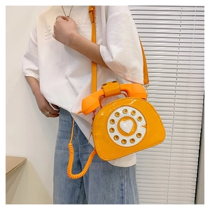Close-up of orange retro telephone crossbody bag with vintage dial and heart detail