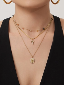 Detail of layered gold necklaces with crucifix cross and oval saint medal pendants