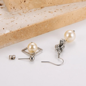 Detailed view of asymmetric stainless steel pearl earrings with a square frame and knot