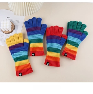 Flat lay of colorful rainbow striped knitted gloves with ribbed cuffs on white surface
