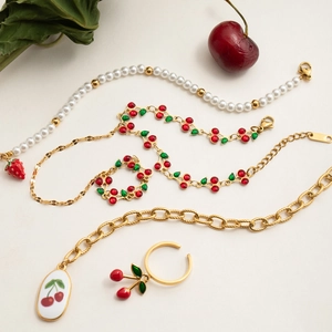 Detail view of 18K gold plated cherry jewelry set with pearls and red enamel