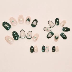 Detail of dark green and pink press-on nails with golden starburst and bow designs