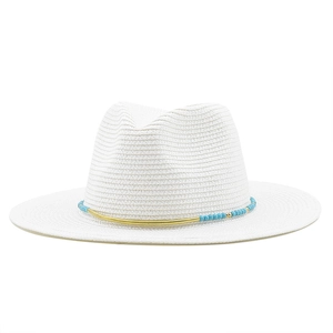 Detailed texture of white straw hat with sky blue beads and golden metal decorative band