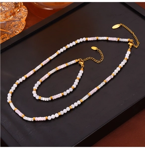 Close-up of handmade white and pink beaded jewelry set with gold spacers on tray
