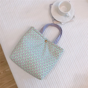 Detail of floral canvas tote bag with purple handles and gold snap button closure